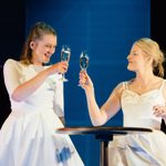 Two women in wedding dresses toasting champagne, a production shot from New Views 2022 winning play 'Barrier(s)' at the Dorfman Theatre, 2022