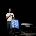 'Model Behaviour' by Jon Brittain, performed by St Thomas the Apostle School and Sixth Form. A young person, standing hand-on-heart next to a podium with the UN crest.