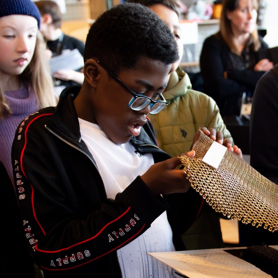 Young person touching costume chainmail during The Witches schools touch tour