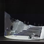 Model box with grand staircase and person playing grand piano at the bottom