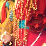 A close-up of brightly coloured outfits and long necklaces on clothes dummys.