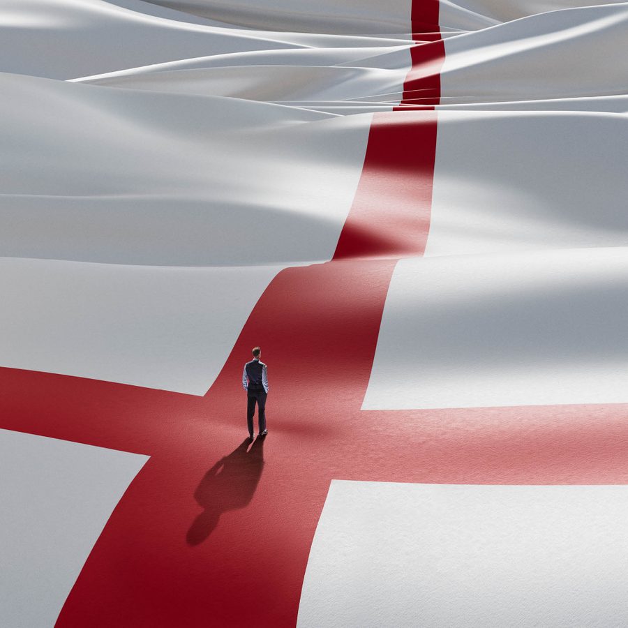 A lone figure stands, his back to us, wearing a waistcoat, shirt and trousers, in the centre of the red cross of the England flag that appears as a landscape rolling off into the distance.