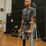 A man with crutches stands, mid speech.