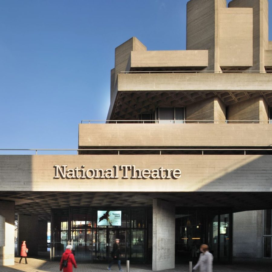 National Theatre building, main entrance exterior with name in raised lettering on the lower terrace balcony and people walking in the square in front.