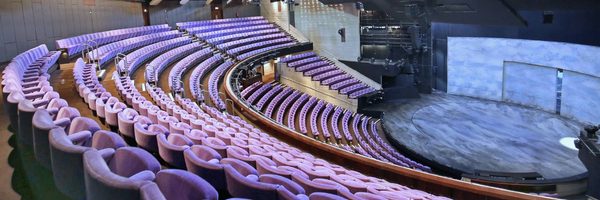 Inside the Olivier Theatre auditorium, with purple cloth-covered seats in a fan shape, descending to a circular stage.