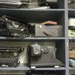 A selection of old typewriters on shelves.